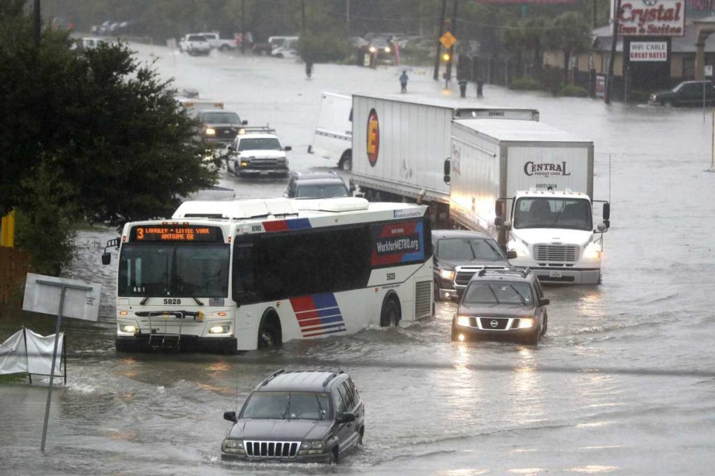 vehicles drive through flooded highway